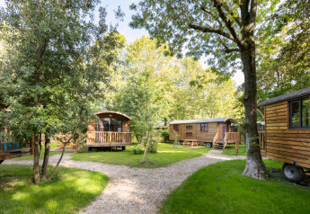 Romantische zigeunerwagens bij Camping de Paris in Frankrijk, te midden van bomen en kronkelende paden.