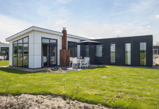 Moderne L-Pavilion lodge bij Poort van Zeeland, Nederland, met grote ramen en een buitenterras.