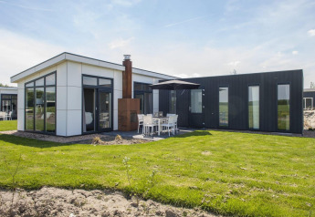 Moderno lodge L-Pavilion al Poort van Zeeland nei Paesi Bassi, con ampie vetrate e patio esterno.