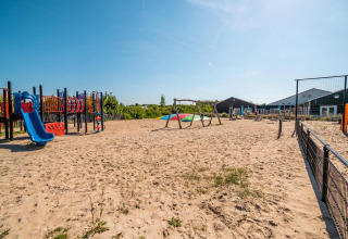 Parco giochi con altalene e scivoli presso il lodge L-Pavilion di Poort van Zeeland, Paesi Bassi, in una giornata di sole.