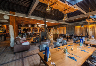 Interno del lodge L-Pavilion a Poort van Zeeland nei Paesi Bassi, arredato in legno e atmosfera accogliente.