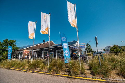 L-Pavilion en Poort van Zeeland, Países Bajos, con banderas y bicicletas en un día soleado.