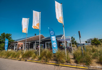 L-Pavilion en Poort van Zeeland, Países Bajos, con banderas y bicicletas en un día soleado.