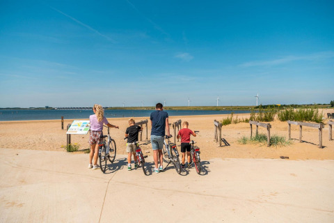 Famille avec enfants et vélos admirant la plage au L-Pavilion, Poort van Zeeland, Pays-Bas.