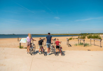 Famille avec enfants et vélos admirant la plage au L-Pavilion, Poort van Zeeland, Pays-Bas.