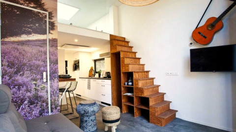 Modern interieur in Tiny House at De Zanding, Nederland, met houten trap, keuken en een gitaar aan de muur.