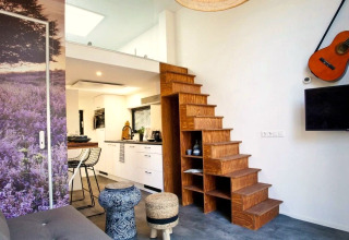 Modern interieur in Tiny House at De Zanding, Nederland, met houten trap, keuken en een gitaar aan de muur.