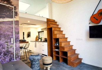 Modernes Interieur im Tiny House at De Zanding, Niederlande, mit Holztreppe, Küche und Gitarre.