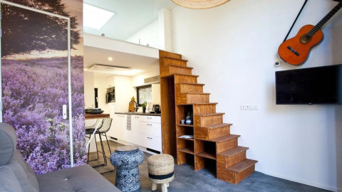 Modern tiny house interior at Tiny House at De Zanding, Netherlands, featuring wooden stairs and kitchen.