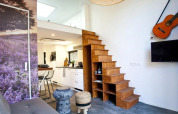 Modern interieur in Tiny House at De Zanding, Nederland, met houten trap, keuken en een gitaar aan de muur.
