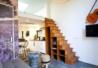 Moderne lille boliginteriør i Tiny House at De Zanding, Holland, med trætrappe, køkken og guitar.