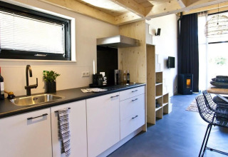 Moderne, compacte keuken en woonkamer in een Tiny House bij De Zanding, Nederland, stijlvol ingericht.