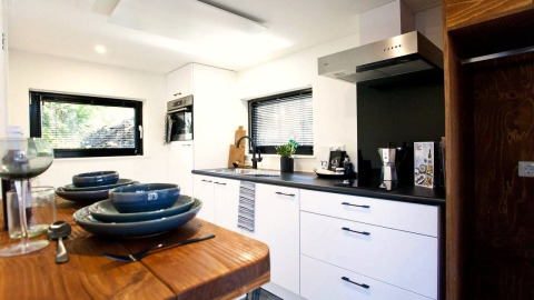 Moderne keuken in Tiny House at De Zanding, Nederland, met eettafel en stijlvol zwart-wit interieurontwerp.