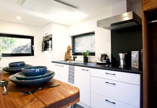 Moderne keuken in Tiny House at De Zanding, Nederland, met eettafel en stijlvol zwart-wit interieurontwerp.