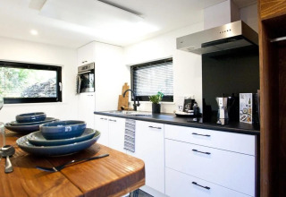 Cucina moderna nel Tiny House at De Zanding, Paesi Bassi, con tavolo da pranzo in primo piano e stile elegante.