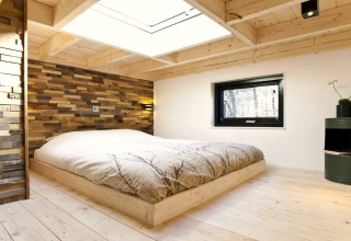 Moderne slaapkamer in Tiny House bij De Zanding, Nederland, met houten decor en groot dakraam.