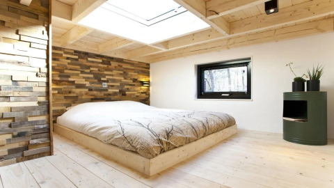 Modern bedroom in Tiny House at De Zanding, Netherlands, with wood decor and large skylight window.