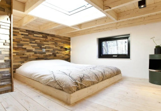 Modern bedroom in Tiny House at De Zanding, Netherlands, with wood decor and large skylight window.