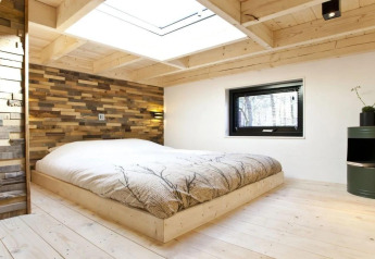 Moderne soveværelse i Tiny House ved De Zanding, Holland, med trævægge og stort ovenlysvindue.