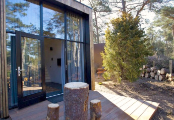 Modernes Tiny House bei De Zanding in den Niederlanden mit großen Glasfenstern und Holzterrasse im Wald.