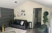 Sala moderna en la cabaña Berkel de De Zanding, Países Bajos, con sofá gris y decoración vegetal.