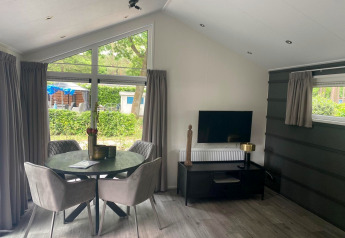 Modern Berkel lodge at De Zanding, Netherlands, with dining area, TV, round table and elegant decor.
