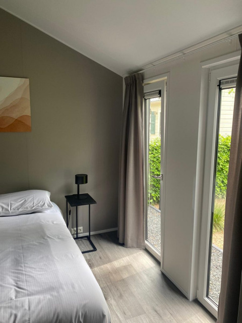 Chambre moderne à la cabane Berkel de De Zanding, Pays-Bas, avec grandes fenêtres et décoration minimaliste.