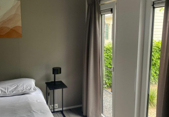 Chambre moderne à la cabane Berkel de De Zanding, Pays-Bas, avec grandes fenêtres et décoration minimaliste.