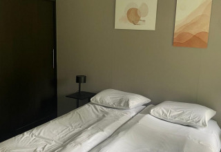Twee single bedden met wit beddengoed in een kamer van de Berkel-lodge op De Zanding, Nederland.
