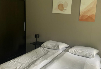 Deux lits simples avec draps blancs dans une chambre moderne au Berkel lodge, De Zanding, Pays-Bas.