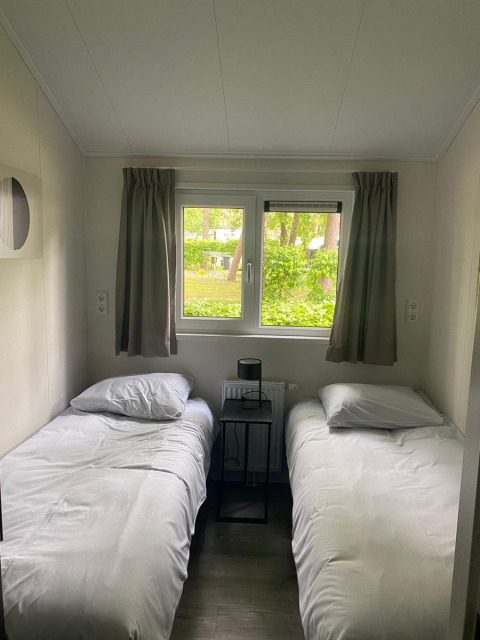 Kamer in de Berkel-lodge van De Zanding, Nederland, met twee enkele bedden en zicht op groen.