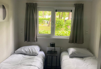 Kamer in de Berkel-lodge van De Zanding, Nederland, met twee enkele bedden en zicht op groen.
