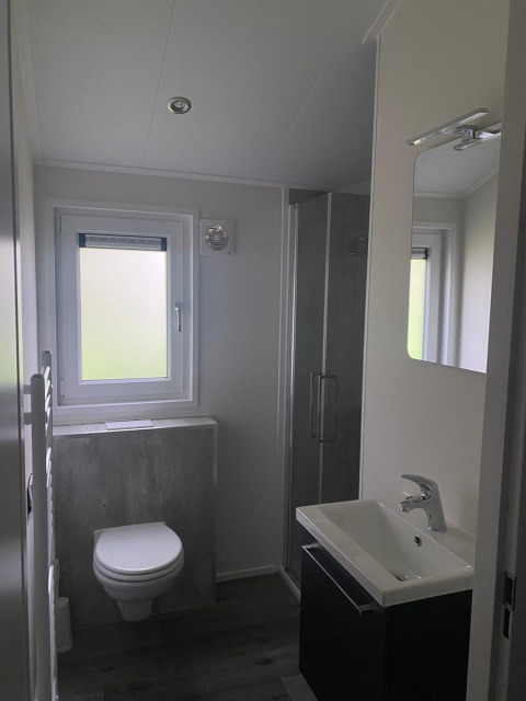 Moderne badkamer met zwevend toilet, wastafel, spiegel en douche in de Berkel-lodge te De Zanding, Nederland.