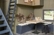 Innenraum des Tiny House bei De Zanding, Niederlande, mit Holztisch, Bänken, Kissen und Fellen.