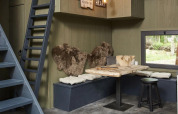 Interieur van Tiny House op De Zanding, Nederland, met houten tafel, banken, kussens en vachten.