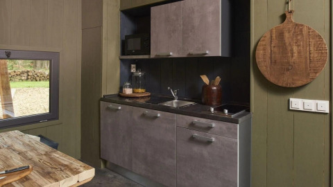 Moderne, compacte kitchenette in Tiny House bij De Zanding, Nederland, met houten tafel en keukengerei.