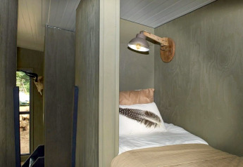 Indvendigt billede af en seng med væglampe i Tiny House på De Zanding i Holland, med hyggelig stemning.