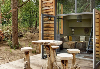 Udendørs træmøbler og hyggelig opholdsstue i en lille hytte i skoven ved Tiny House at De Zanding i Holland.