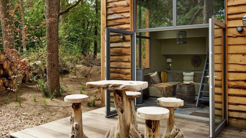 Rustic wooden furniture outside a cozy tiny house at De Zanding, surrounded by forest in the Netherlands.