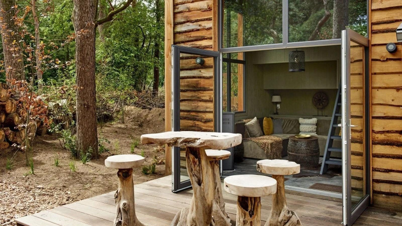 Muebles rústicos de madera fuera de una tiny house acogedora en De Zanding, rodeada de bosque en Holanda.