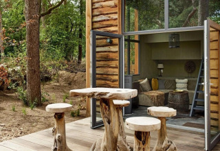 Rustic wooden furniture outside a cozy tiny house at De Zanding, surrounded by forest in the Netherlands.