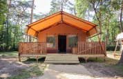 Tienda safari Lodgetent en De Zanding, Países Bajos, rodeada de árboles y con terraza delantera.