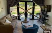 Sala de estar en Forest Lodge, De Zanding, Países Bajos, con grandes puertas de vidrio y tablones cruzados.
