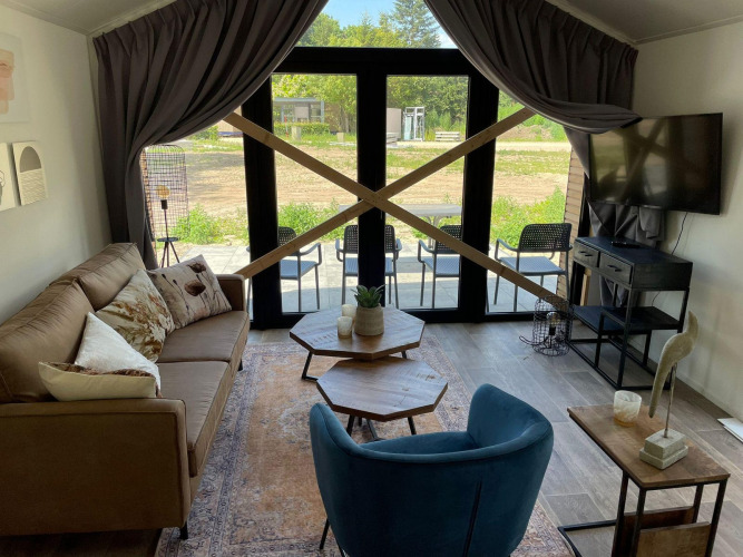 Sala de estar en Forest Lodge, De Zanding, Países Bajos, con grandes puertas de vidrio y tablones cruzados.