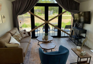 Sala de estar en Forest Lodge, De Zanding, Países Bajos, con grandes puertas de vidrio y tablones cruzados.