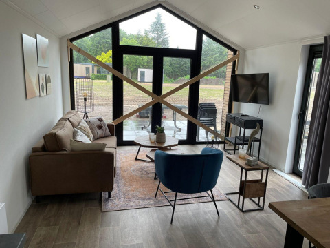 Woonkamer van Forest Lodge bij De Zanding, Nederland, met grote ramen en houten latten in kruisvorm.