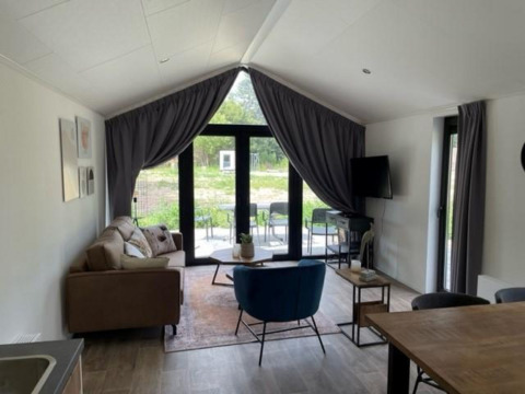 Innenansicht der Forest Lodge im De Zanding, Niederlande, mit moderner Einrichtung und großen Fenstern.