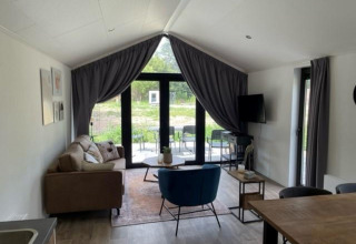 Vue intérieure de la Forest Lodge à De Zanding, Pays-Bas, avec mobilier moderne et grandes fenêtres.