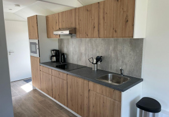 Moderne køkken i Forest Lodge på De Zanding, Holland, med træskabe, kogeplade, vask og kaffemaskine.
