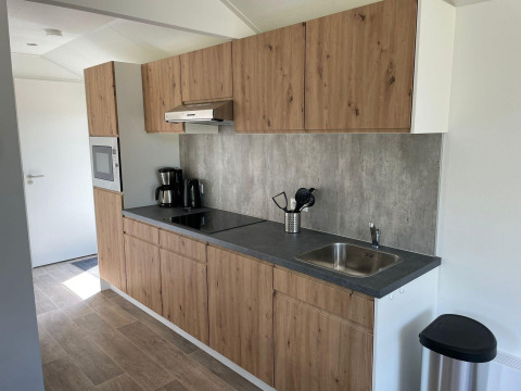 Moderne køkken i Forest Lodge på De Zanding, Holland, med træskabe, kogeplade, vask og kaffemaskine.